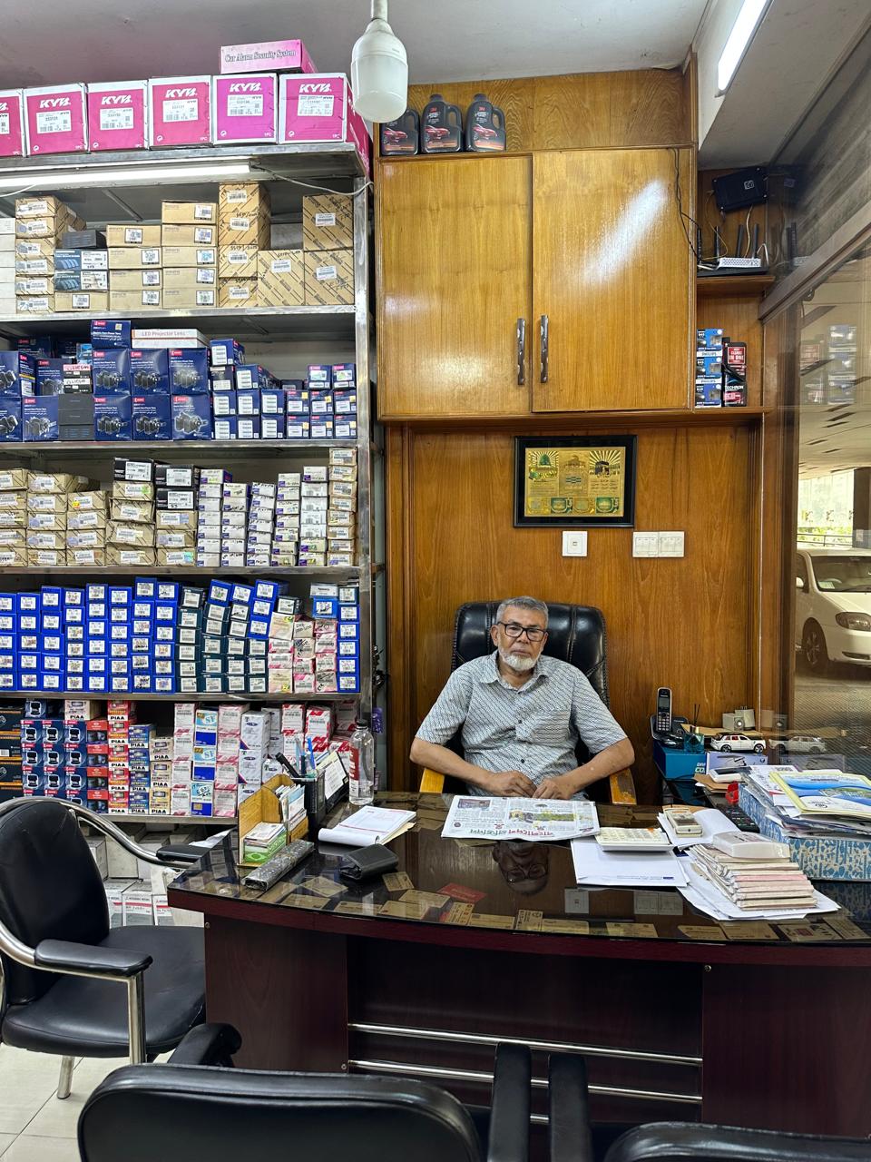 Founder of Jaman Autos at his desk surrounded by genuine auto parts